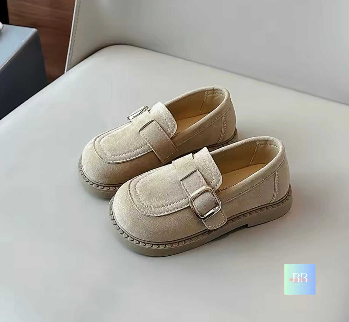 Pair of beige loafers with buckles on a light surface