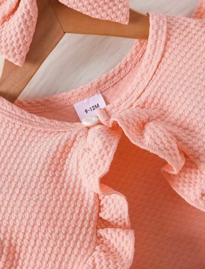Close-up of a pink textured garment with a size tag on a light wooden surface.