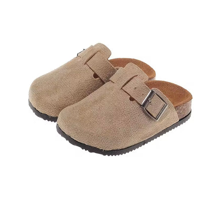 Pair of beige suede clogs with a buckle on a white background
