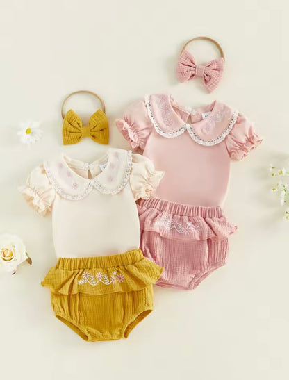 Two baby outfits with ruffled collars and matching headbands on a light background