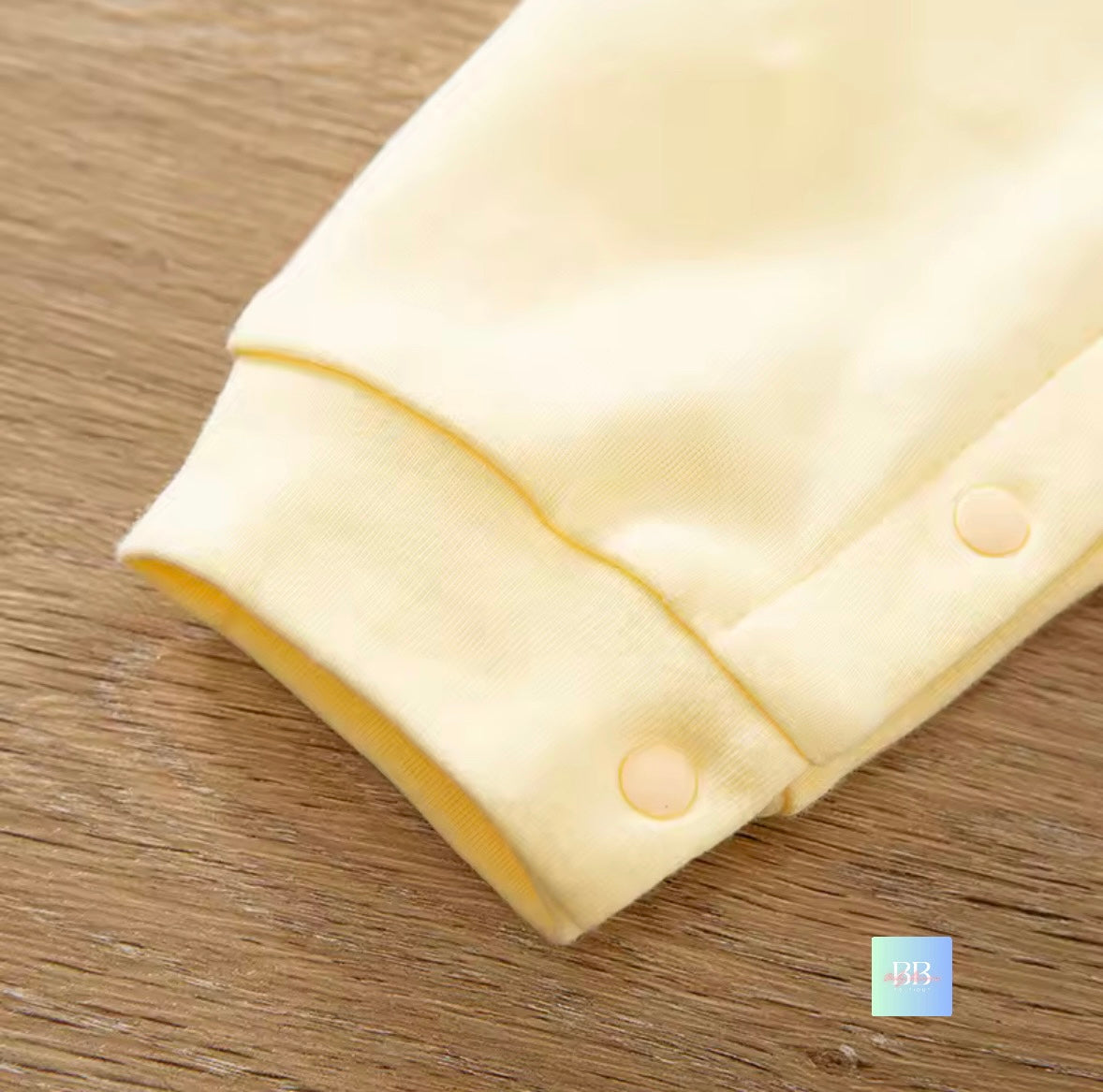 Folded cream-colored fabric with buttons on a wooden surface