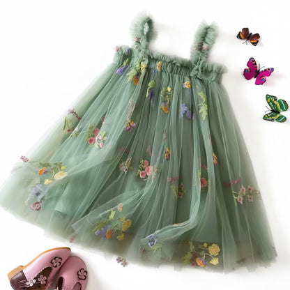 Green embroidered dress on a textured surface with flowers and butterflies.