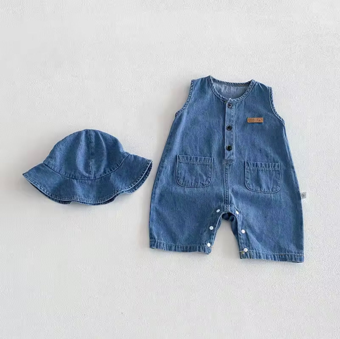 Denim baby romper and hat set on a light gray background