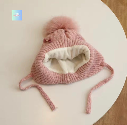 Pink knitted hat with a pom-pom on a white surface