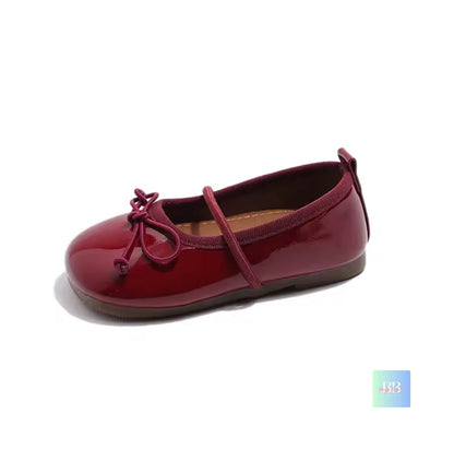 Maroon patent leather shoe with a bow on a white background