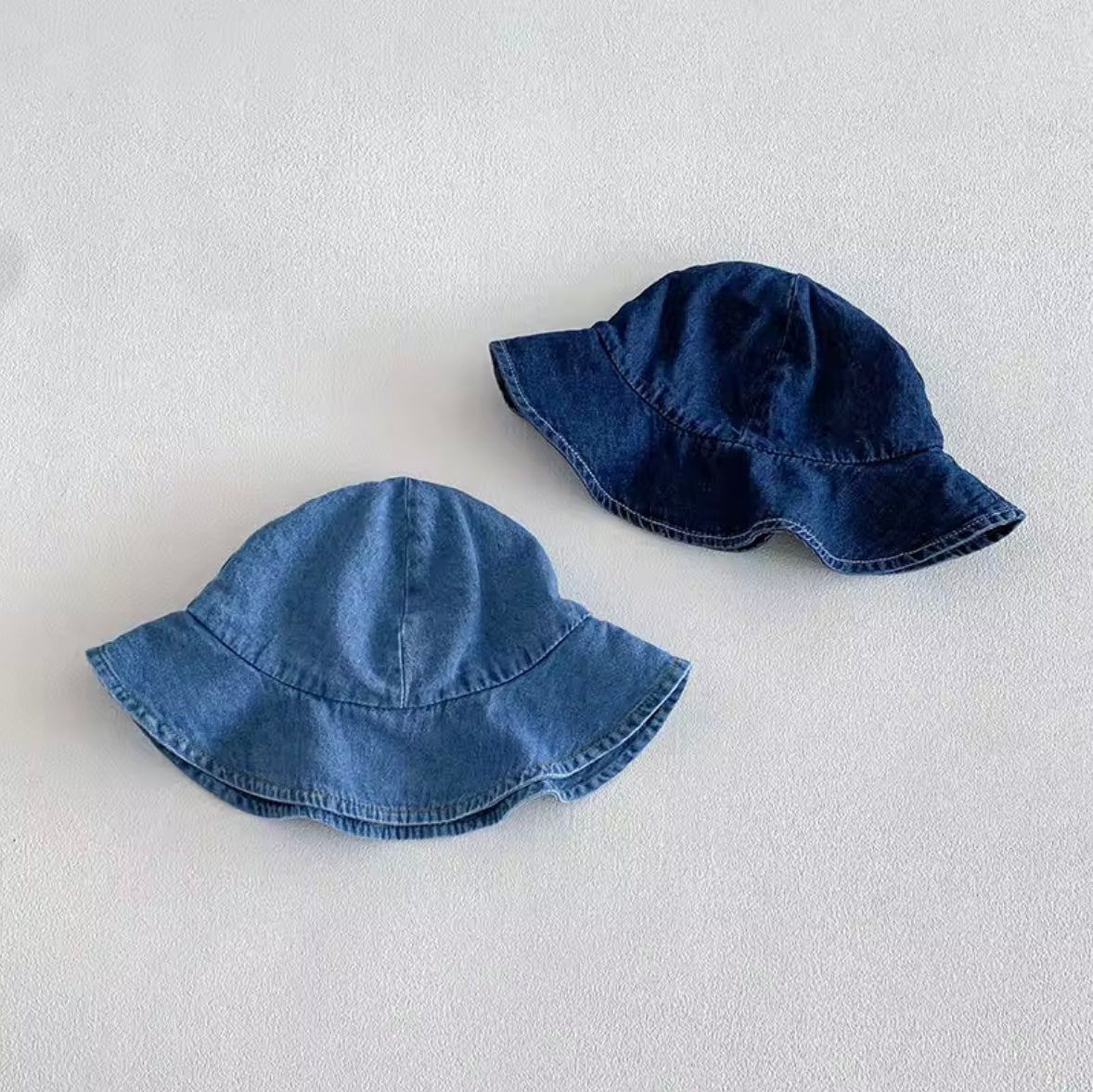 Two denim bucket hats on a light gray background