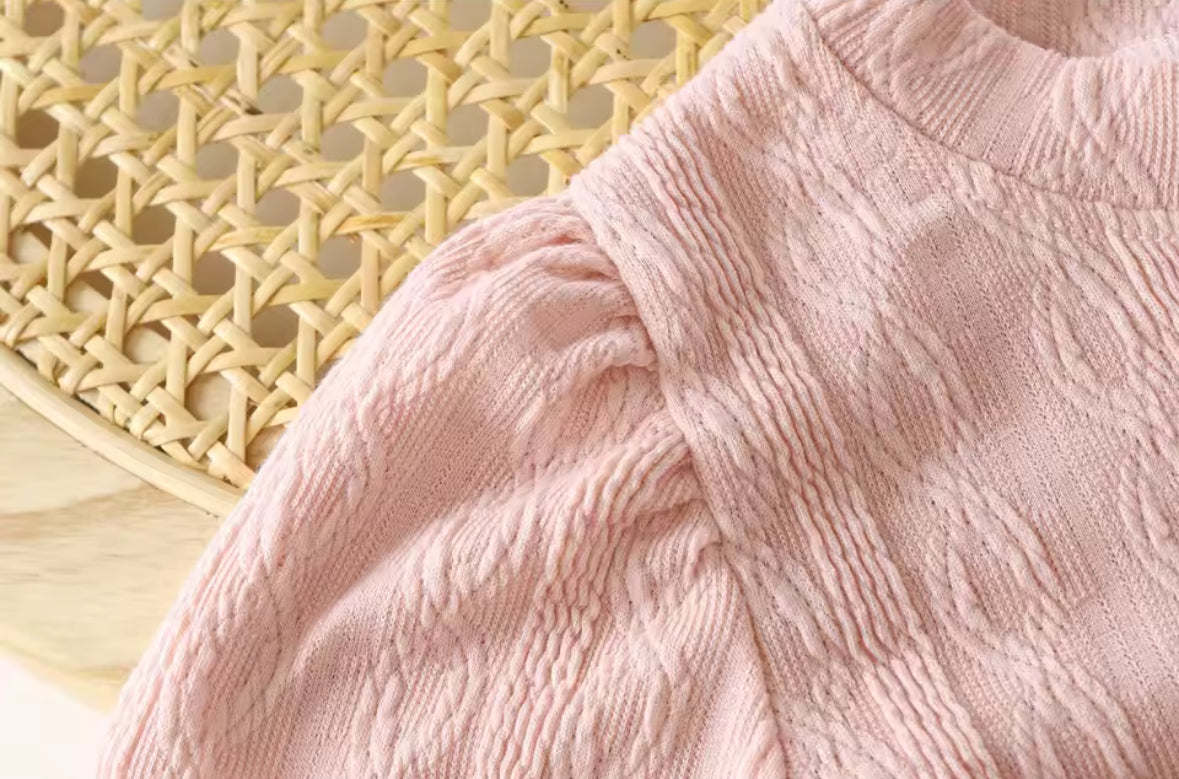 Close-up of a pink textured fabric with a woven mat in the background