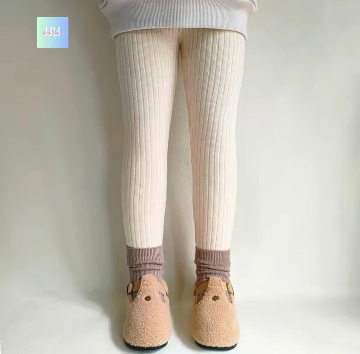 White tights worn with beige shoes on a plain background