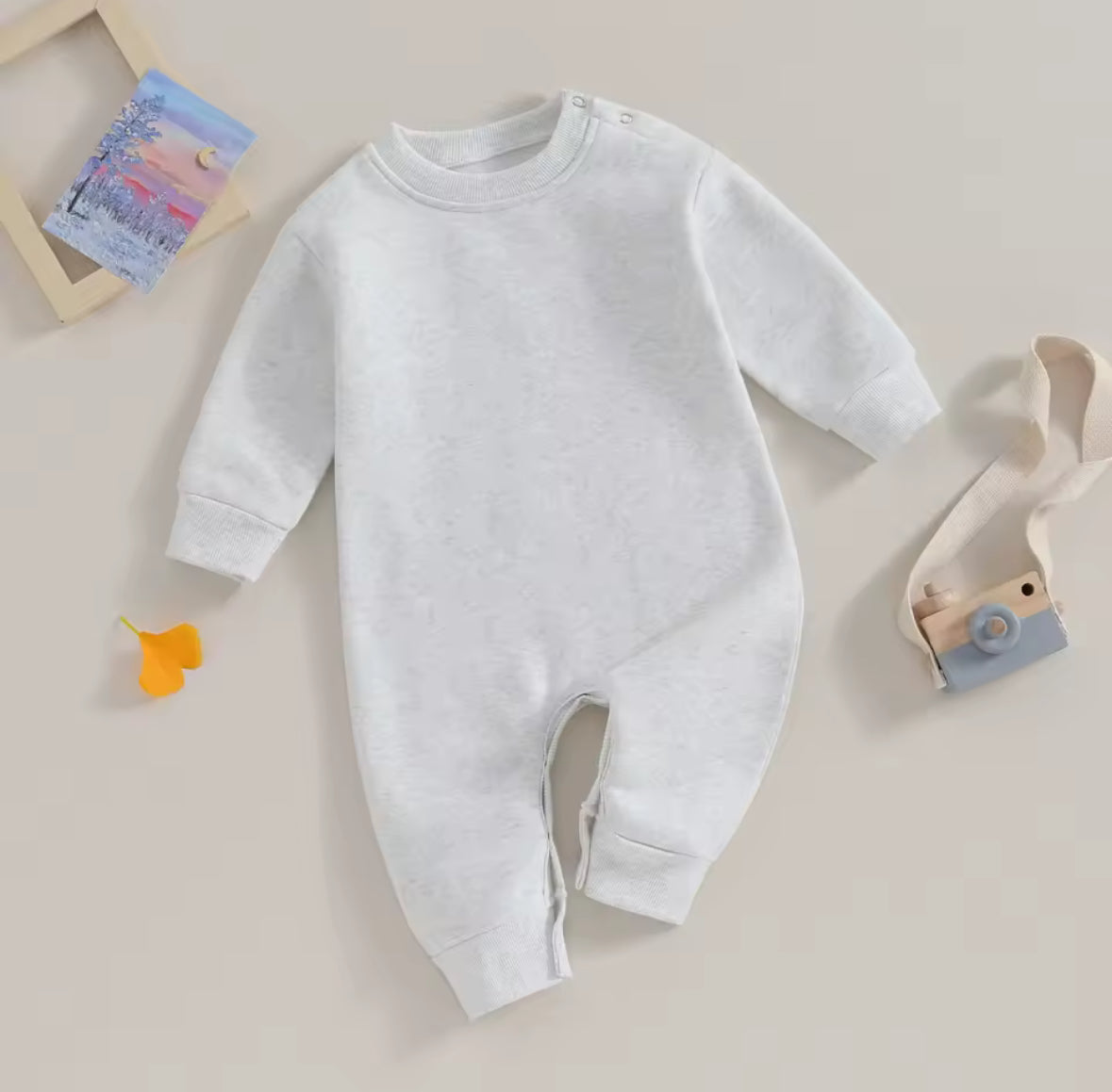 White baby onesie on a light beige background