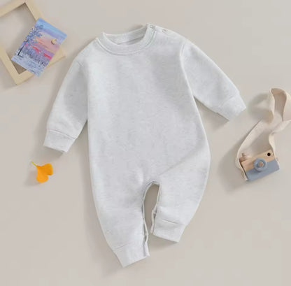 White baby onesie on a light beige background
