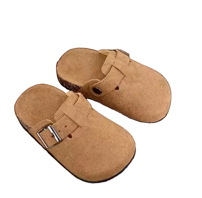 Brown slippers with a buckle on a wooden surface next to a mug and keyboard.