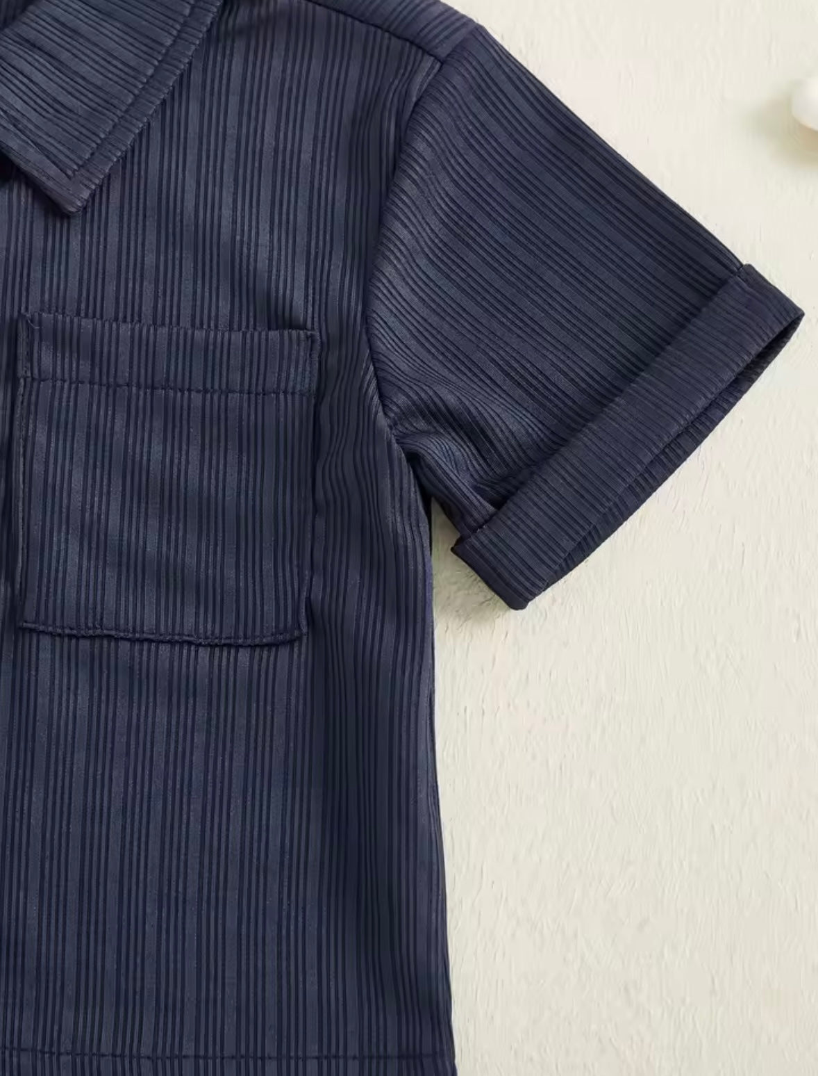 Navy textured shirt with rolled-up sleeves on a light background