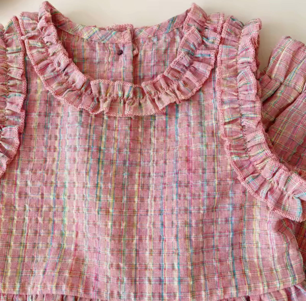Pink plaid fabric with ruffled edges on a plain background