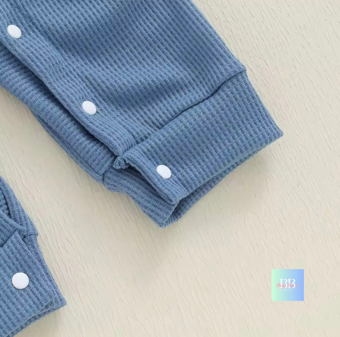 Folded blue textured fabric with white buttons on a light beige surface