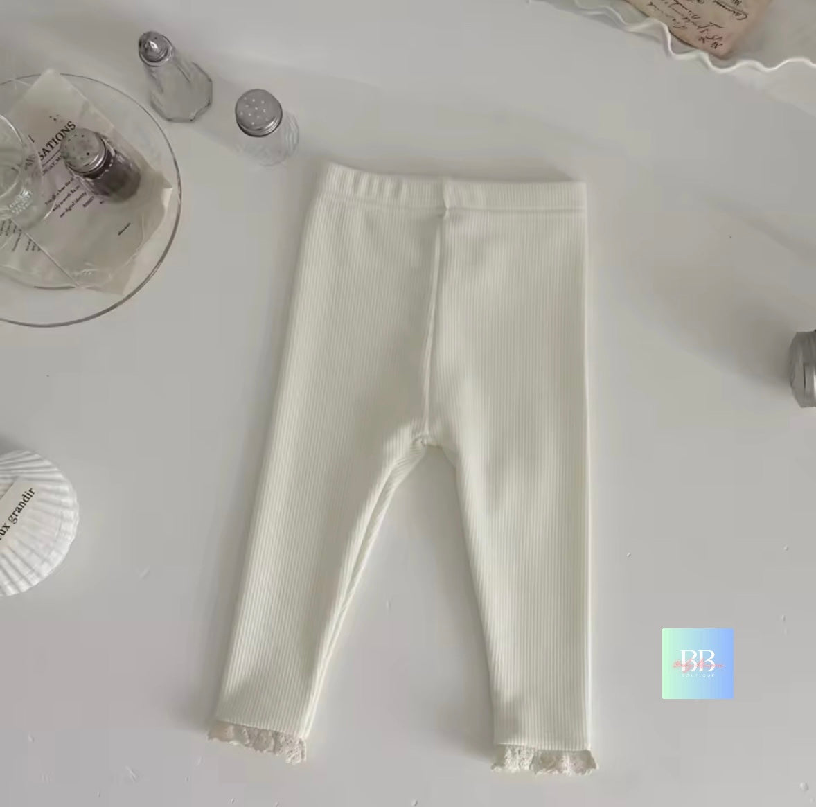 White ribbed leggings on a light gray surface with decorative items.