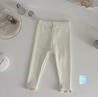 White ribbed leggings on a light gray surface with decorative items.