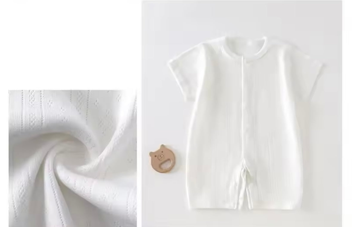 White baby outfit with fabric swatch on a light gray background