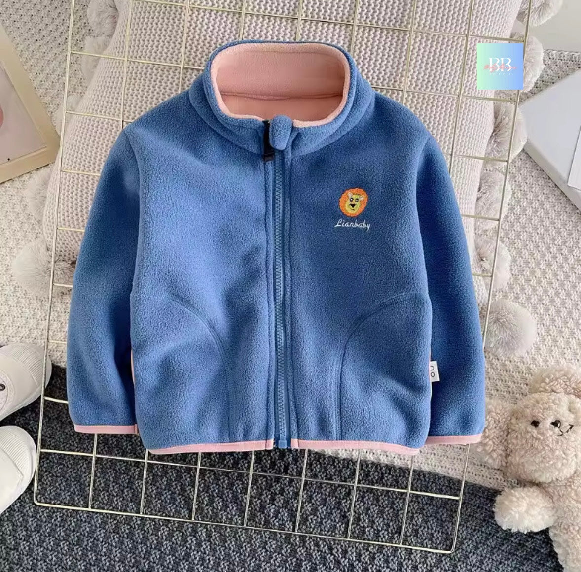 Blue children's jacket with pink trim on a textured surface