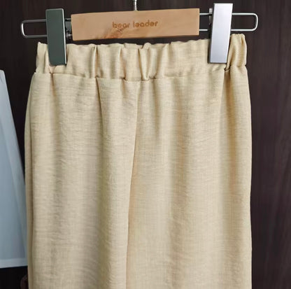 Beige pants on a hanger with 'bear leader' branding against a dark background