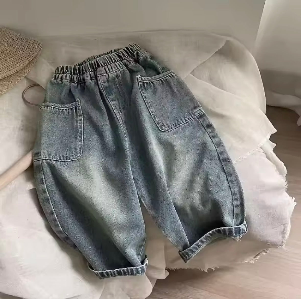 Light blue denim jeans on a white fabric surface