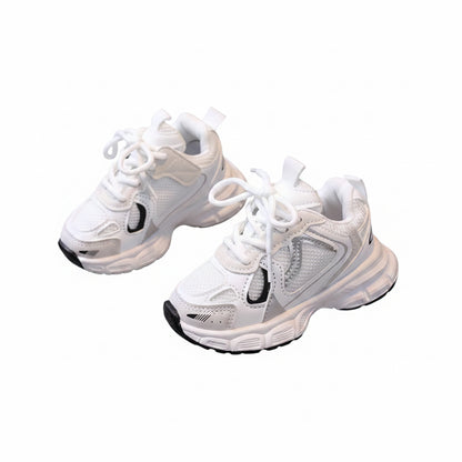 White sneakers with black accents held by a hand on a light surface.