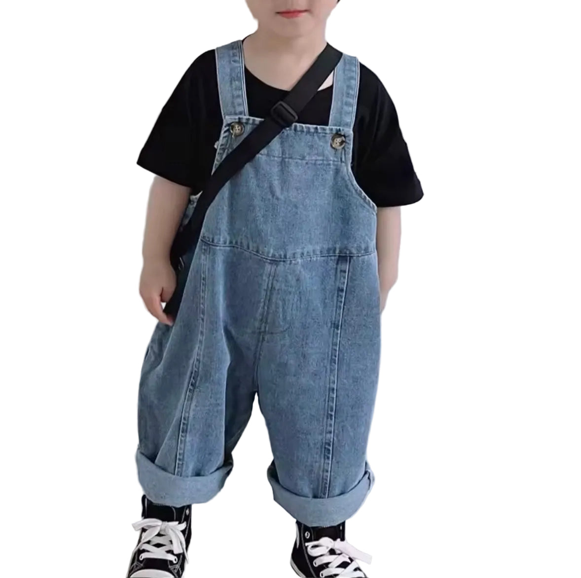 Child wearing denim overalls and a black shirt on a white background
