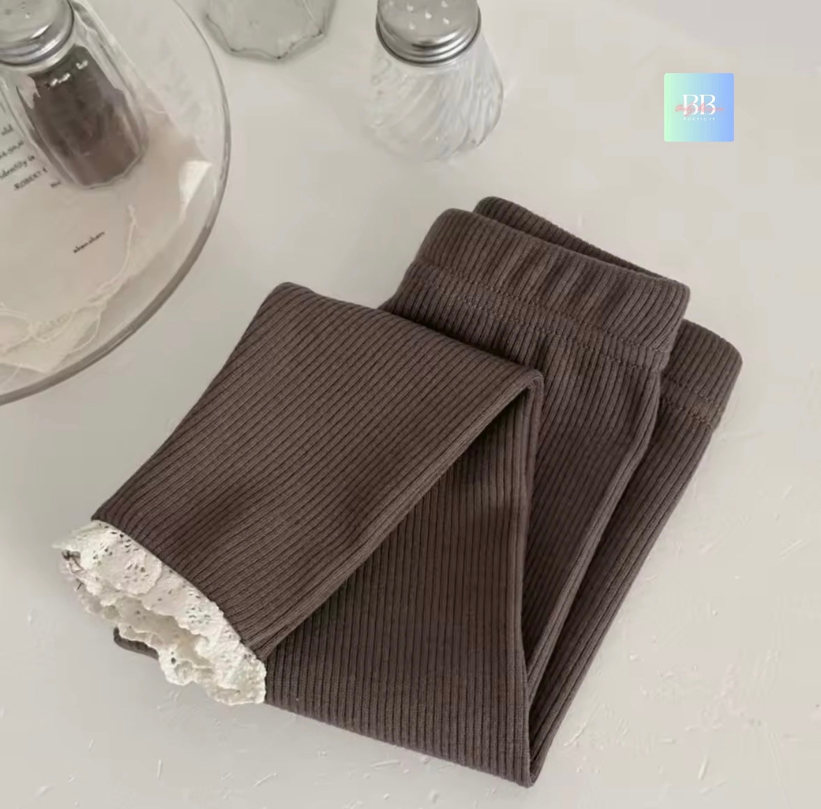 Brown ribbed leggings with lace trim on a white surface