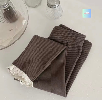 Brown ribbed leggings with lace trim on a white surface