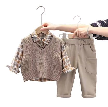 Children's clothing set with sweater vest and pants on hangers against a neutral background