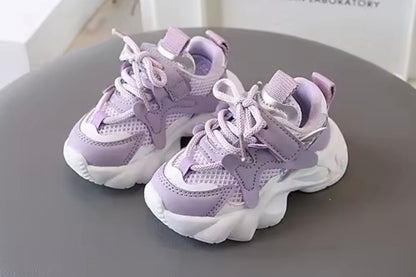 Pair of purple children's sneakers on a gray surface with a white background