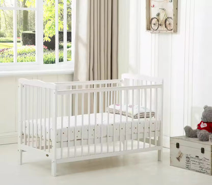 White crib in a bright room with a window and decorative elements.