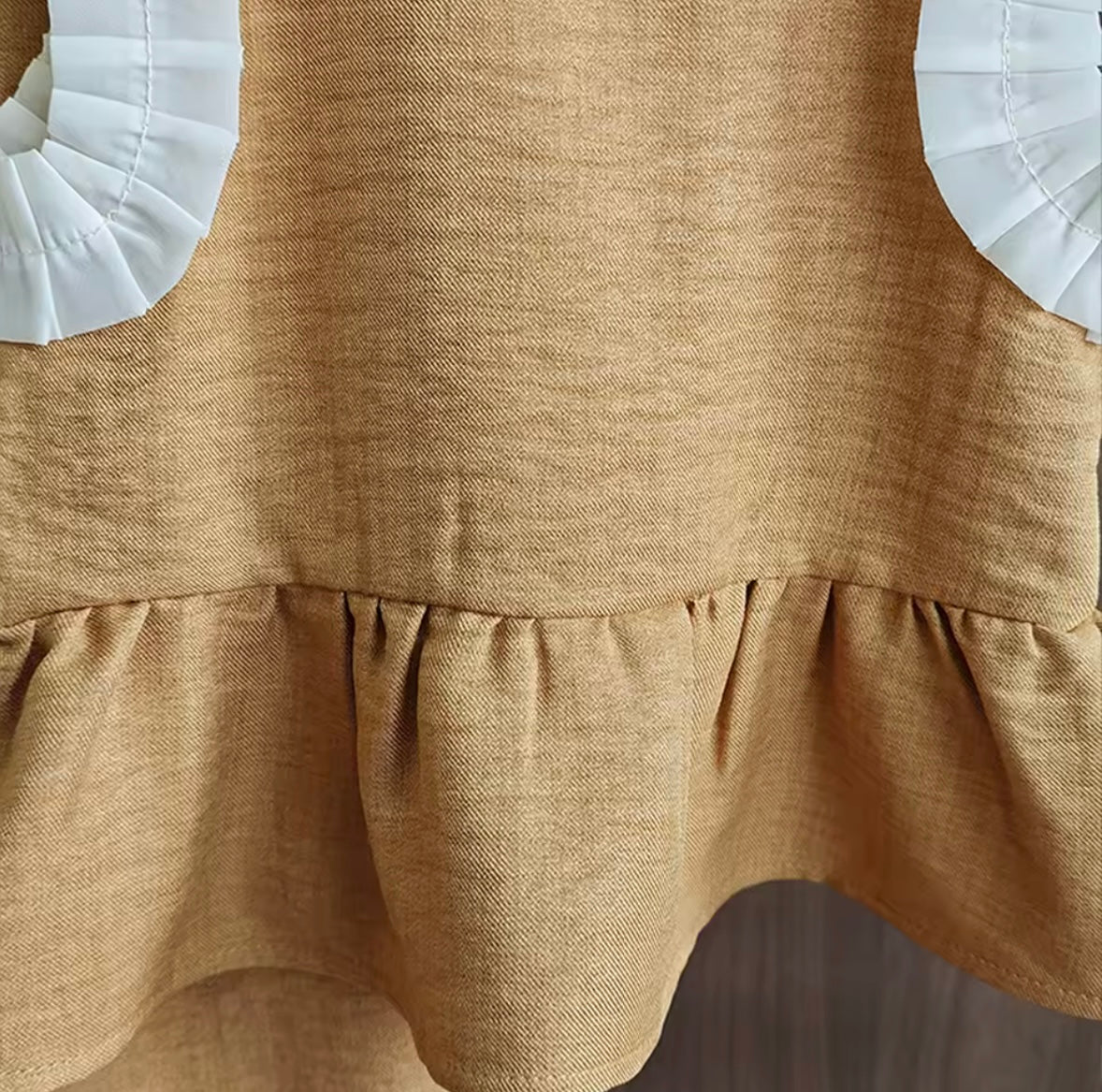 Brown dress with white petal details on a neutral background