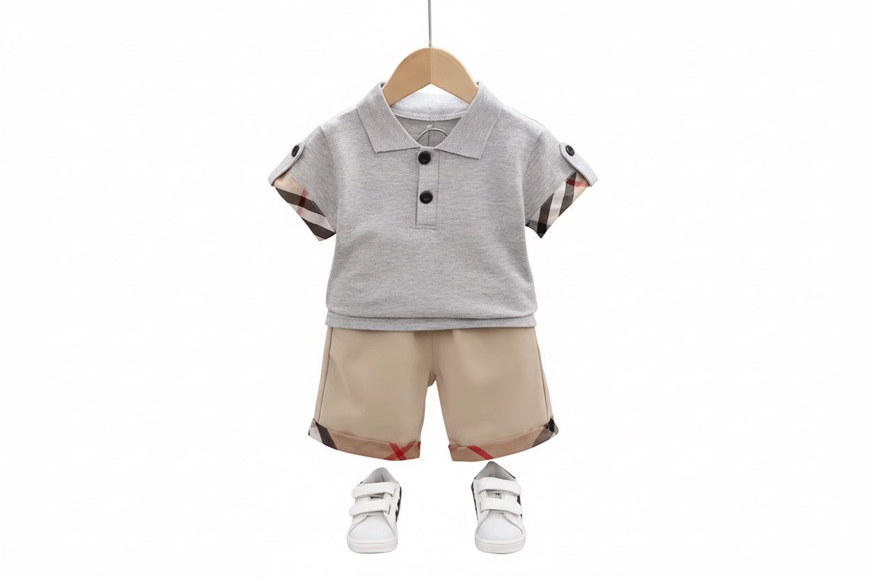 Children's outfit with gray polo shirt and beige shorts on a hanger against a neutral background.