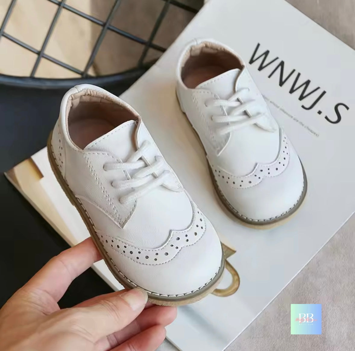 White children's shoes with laces on a box labeled 'WWJ.S'.