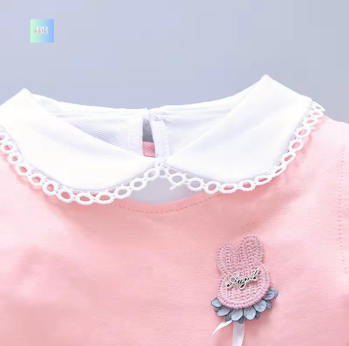 Pink dress with white lace collar and decorative bow on a gray background