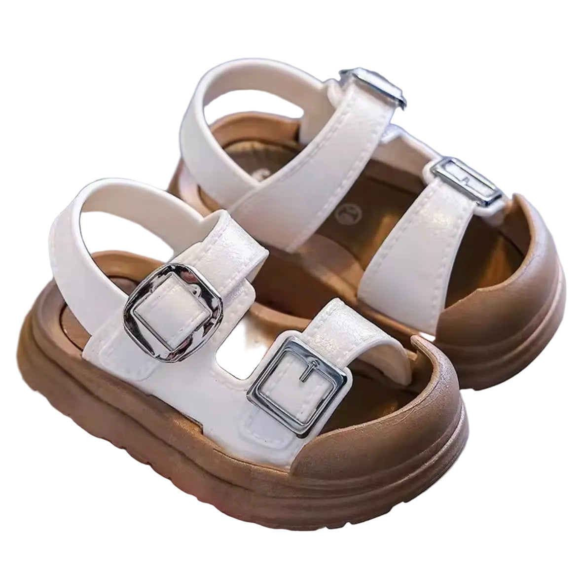 White and brown sandals with buckles held by a hand on a blurred background