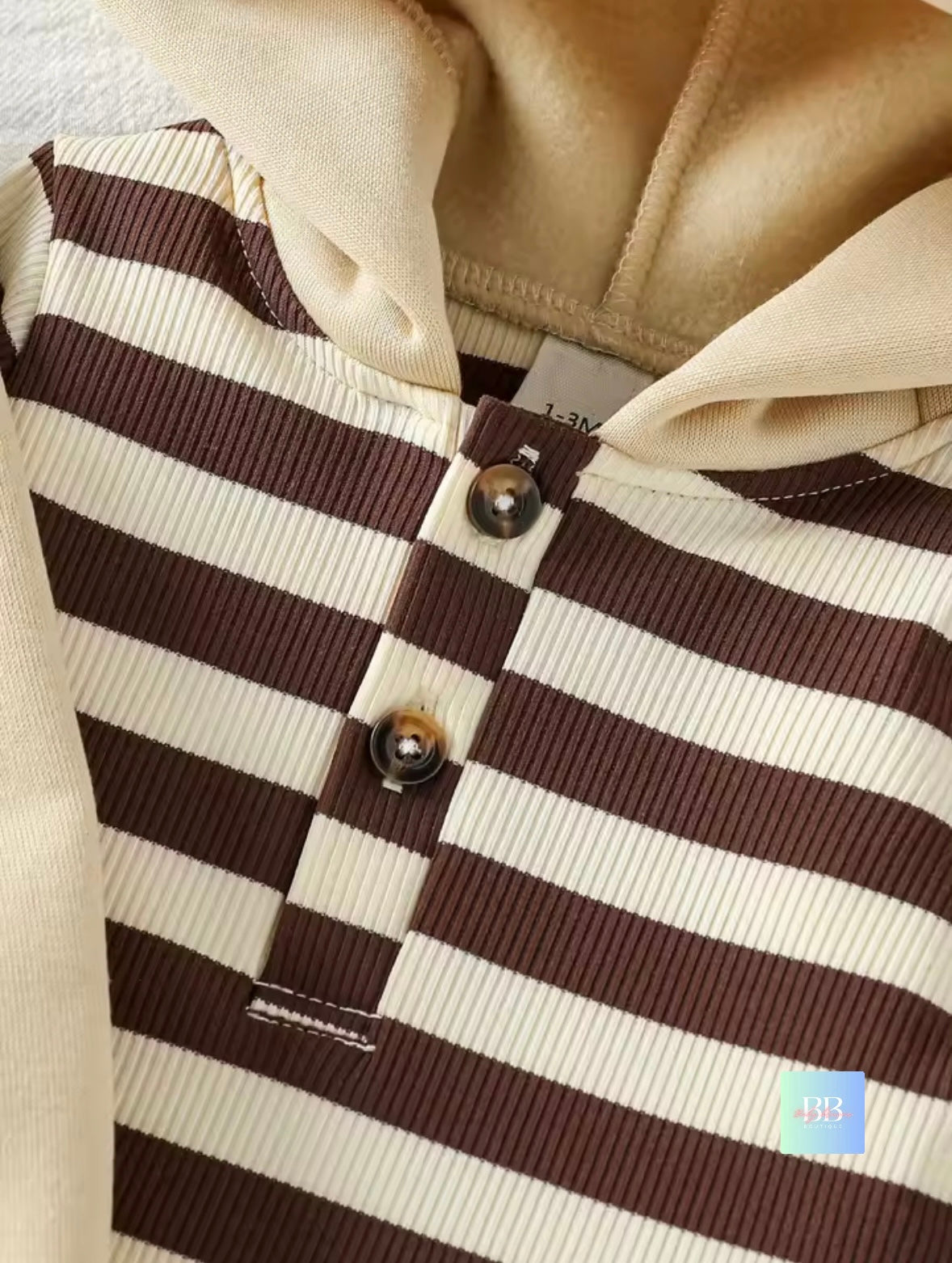 Close-up of a brown and white striped garment with buttons, likely a coat or jacket.