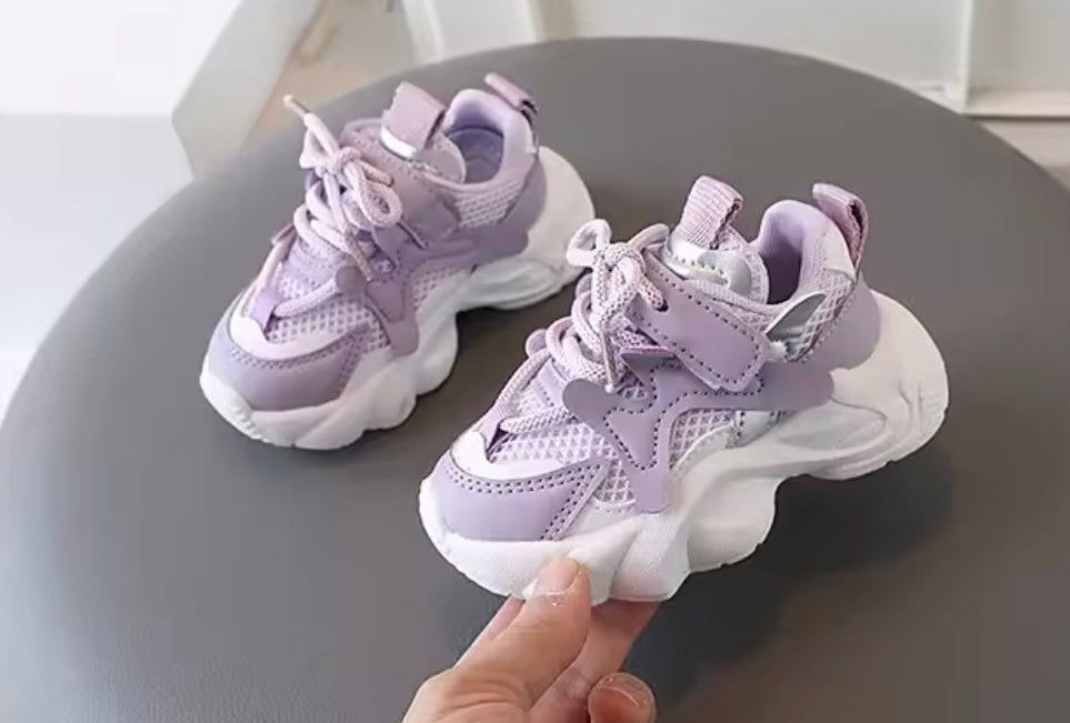 Purple children's sneakers on a gray stool with a blurred background