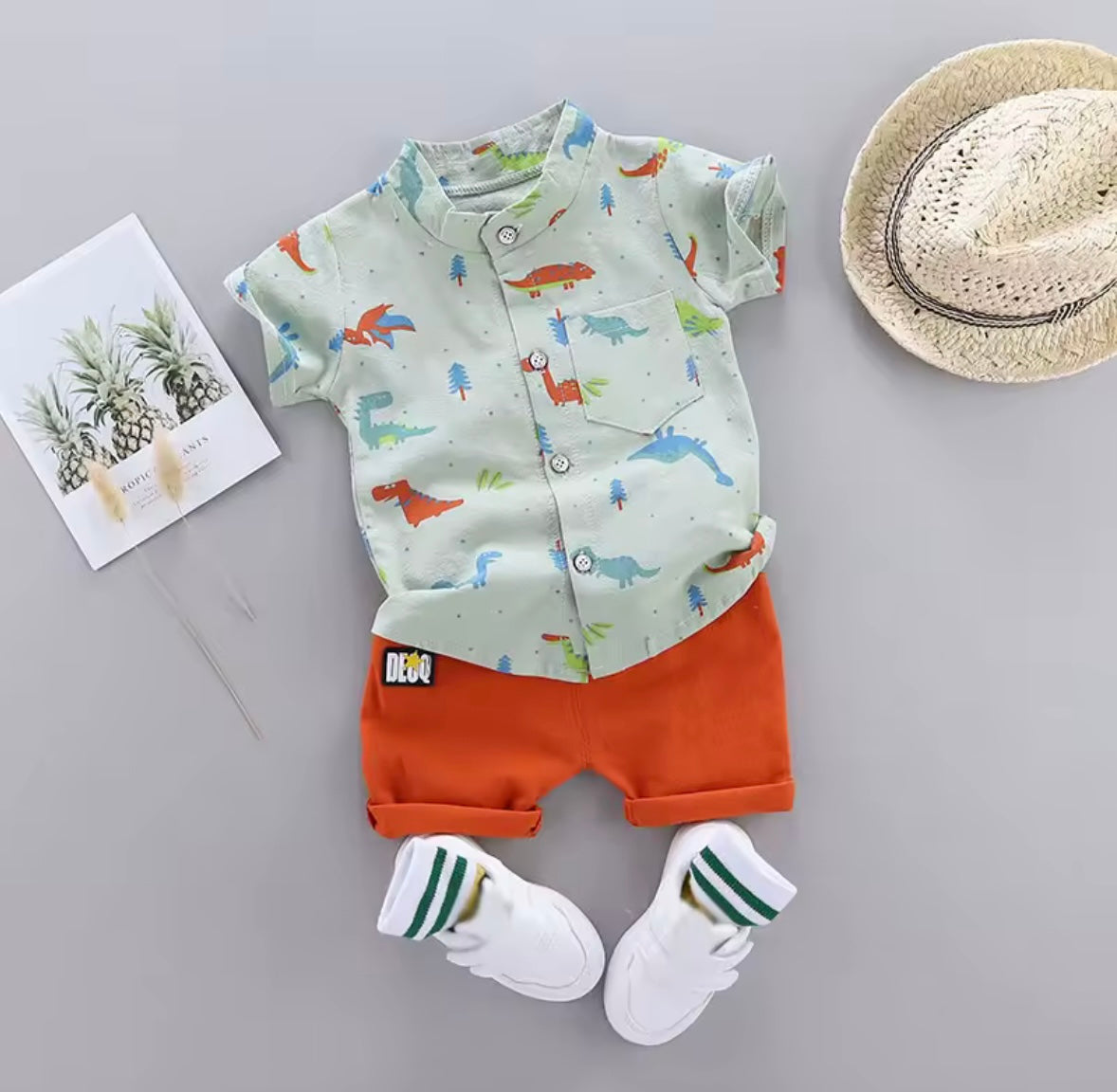 Children's outfit with shirt, shorts, socks, and hat on a gray background