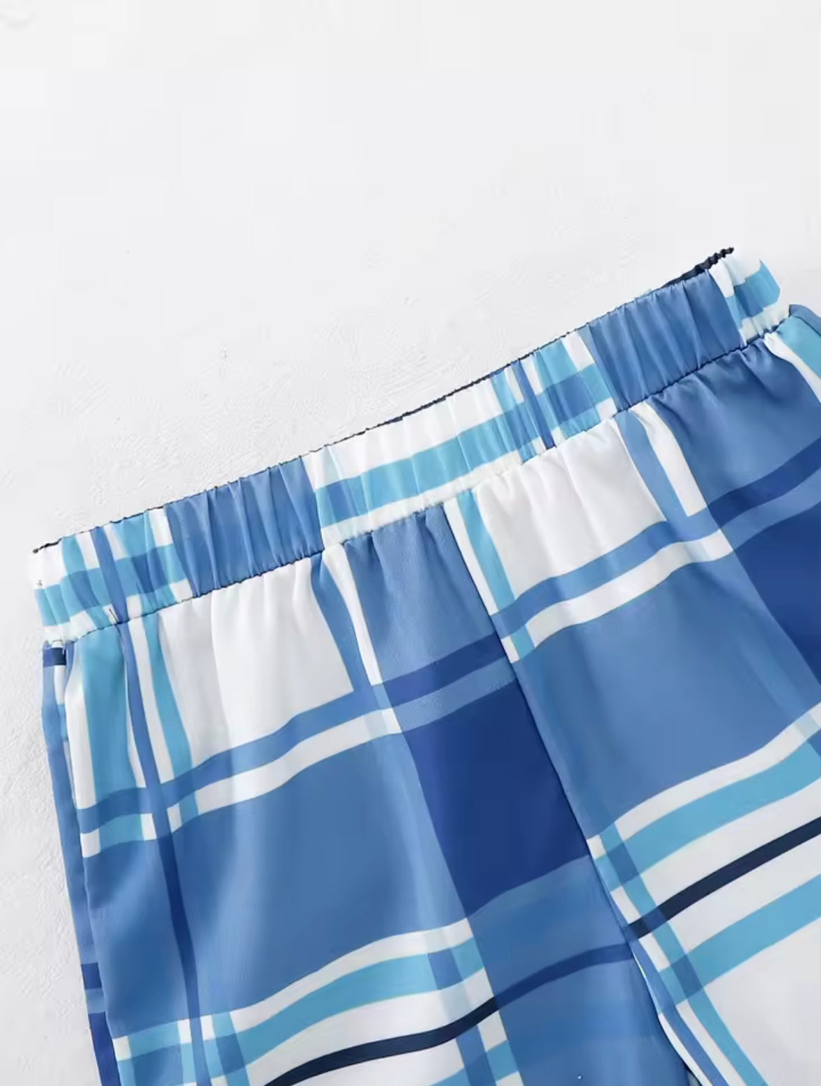 Blue and white plaid shorts on a light gray background
