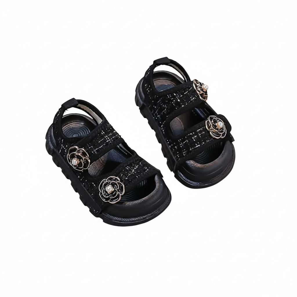 Black sandals with decorative elements on a gray surface
