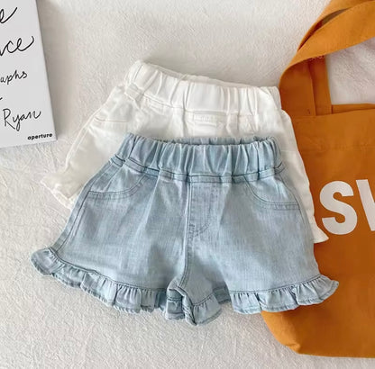 Light blue denim shorts with ruffles on a white surface with an orange bag in the background.