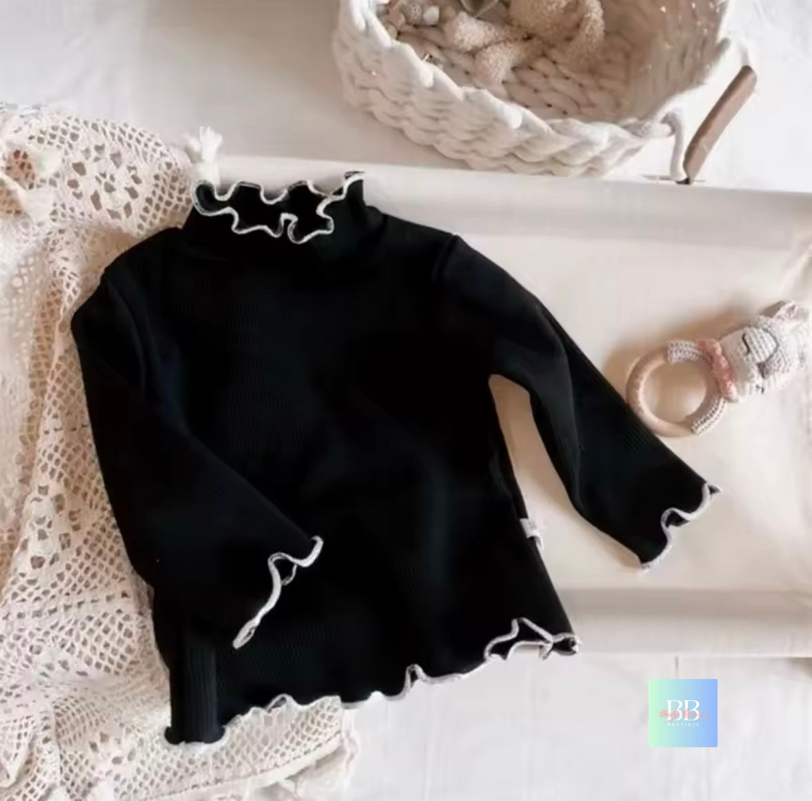 Black long-sleeve top with lace details on a white surface