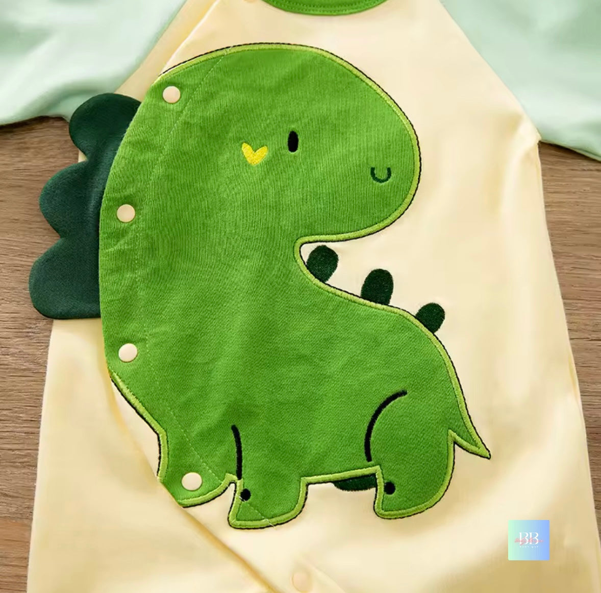Green dinosaur patch on a beige fabric background