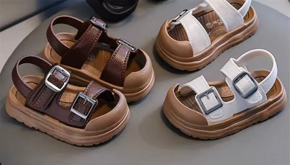 Pair of brown sandals with buckles on a gray surface