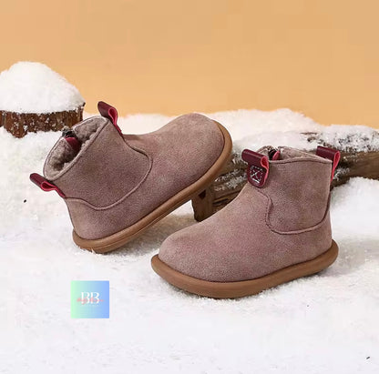 Pair of brown suede boots with red accents on a snowy background