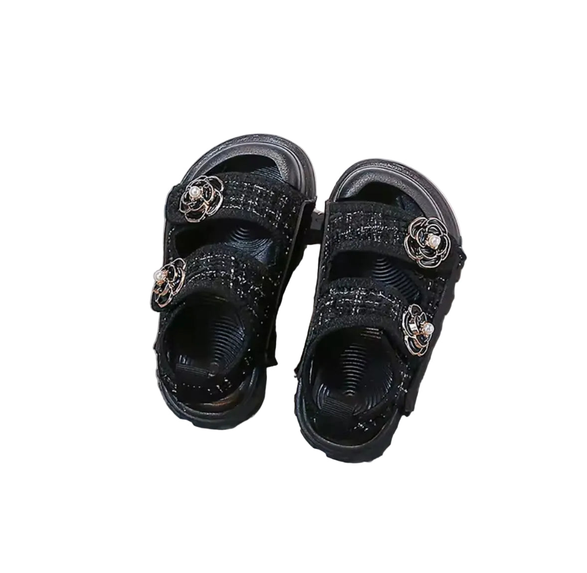 Pair of black sandals with floral embellishments on a gray surface.