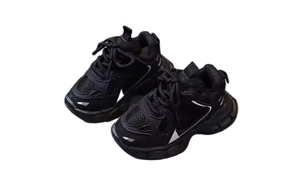 Pair of black sneakers on a white cushioned stool with a wooden floor background
