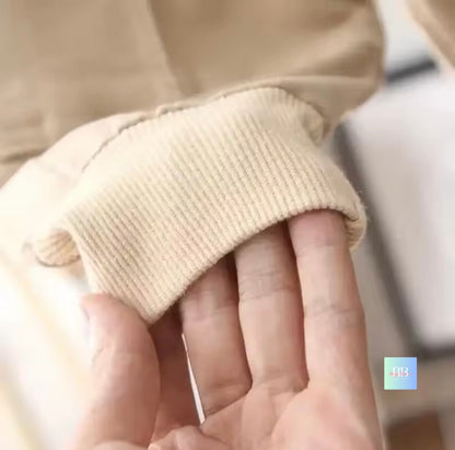 Close-up of a hand wearing beige gloves with a blurred background