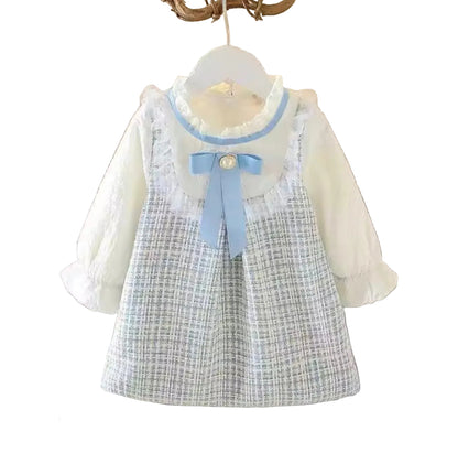 Children's dress with plaid pattern and blue ribbon on a hanger against a light gray background.